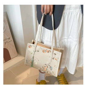 Close-up of beige tote bag with elegant floral embroidery and green tassel detail