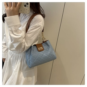 Detalle de bolso tipo cubo acolchado azul claro con cadena dorada y correa de cuero
