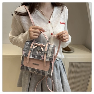 Detail of fashion crossbody bag with pink bow, heart pendant and metal brand name plate