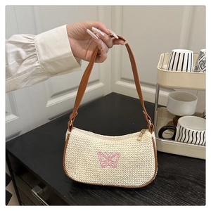Dettaglio della trama in paglia e ricamo a farfalla rosa su borsa a mano color crema