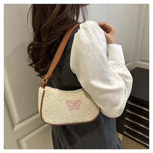 Dettaglio borsa a spalla in paglia beige con ricamo a farfalla rosa e finiture in pelle marrone