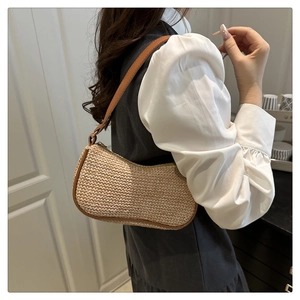 Dettaglio della borsa baguette in paglia con finiture in pelle marrone e zip