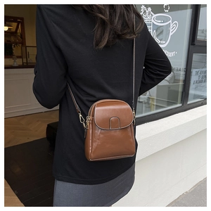 Detail of dark brown mini crossbody bag with double zippers and golden hardware details