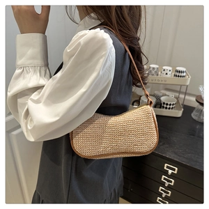 Dettaglio di una borsa a mezzaluna in paglia beige con tracolla in pelle marrone