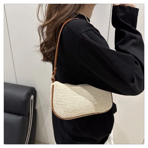 Dettaglio di una borsa sottobraccio in paglia beige con bordi in pelle marrone