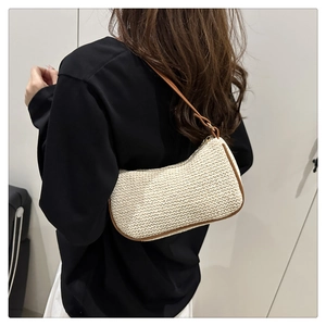 Modella che indossa borsa a spalla in paglia avorio con finiture in pelle marrone