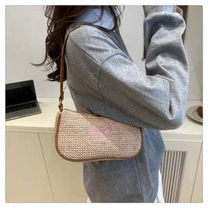 Dettaglio ricamo farfalla rosa su borsa a spalla estiva in paglia intrecciata a mano