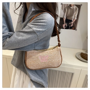 Dettaglio della borsa a spalla in paglia con farfalla ricamata rosa su trama beige intrecciata