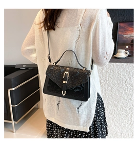 Close-up of black snake pattern envelope flap handbag with gold metal hardware buckle