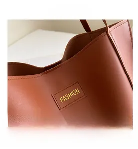 Close-up of caramel leather tote showing lychee texture and fashion logo detail