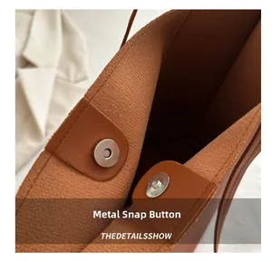 Detail of the high-quality magnetic snap closure on a brown textured leather tote bag