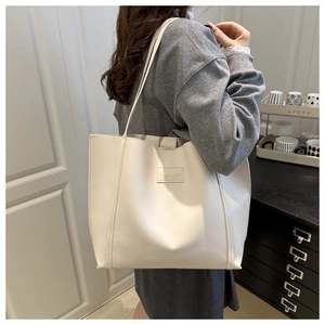 Detailed shot of white PU leather tote bag with FASHION label and slim straps