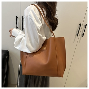 Detailed side view of a tan large tote bag with gold fashion lettering and long straps