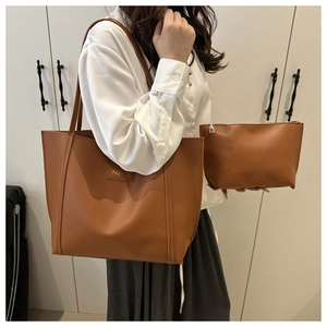 Detail of brown leather tote bag and matching clutch set worn by model in a bright room