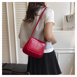 Detail shot of the glossy red saddle bag showing the polished faux leather texture