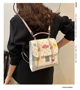 Polka dot backpack with pink leather straps worn by model against a white wall
