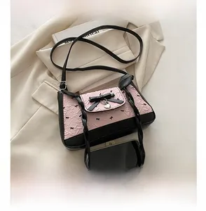 Close-up of pink pleated fabric with a bow detail and heart pendant on a small bag