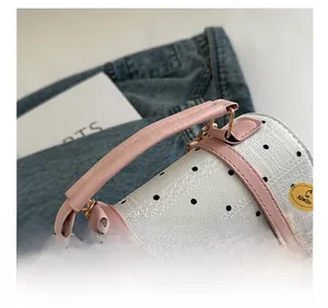 Detailed shot of pink leather handle and polka dot fabric on a stylish women's handbag