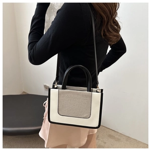 Detail of minimalist tote bag showing white leather and beige fabric contrast textures