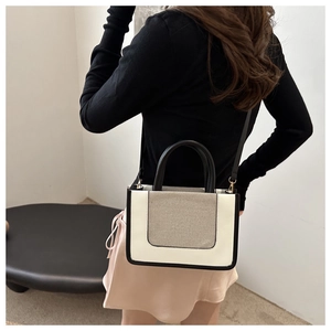 Model view showing the compact color-block crossbody bag with woven texture and top handles