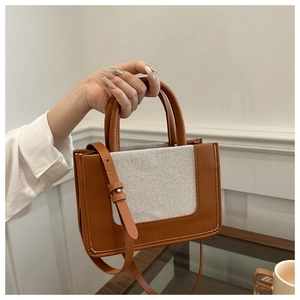 Detail of vintage tote bag featuring brown leather trim and canvas paneling with white stitching