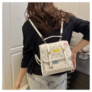 Detail view of cream mini backpack with polka dots and cartoon patches on female model