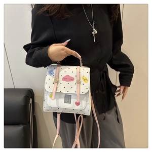 Close-up of white polka dot backpack with pink straps and cartoon style patches