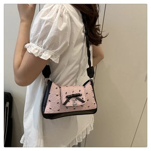 Detailed view of pink bow baguette bag with heart pendant and braided shoulder strap
