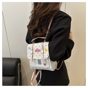 Detail of a white polka dot mini backpack with pink straps and decorative patches