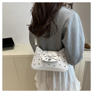 Détail du sac sous l'aisselle en cuir PU blanc avec nœuds noirs et pendentif cœur