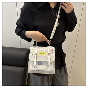 Close-up of white leather shoulder bag with black polka dots and dual woven labels