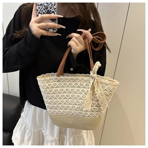 Detail of summer straw tote bag with intricate beige lace crochet and a large side bow