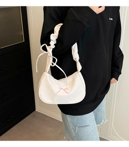 Detail of white nylon crescent bag with ruffled strap and pink embroidered bow