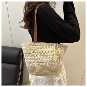Detail of lace floral tote bag with straw woven base and brown leather shoulder strap
