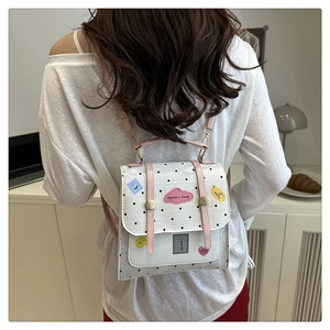 Close-up of small polka dot backpack featuring embroidered patches and pink straps