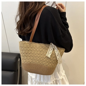 Detail of straw woven tote bag featuring white lace bow and brown leather shoulder strap