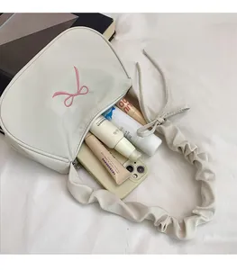 Detailed top view of beige armpit bag with pink bow embroidery and cloud pleated handle