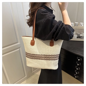 Detail of woven tote bag with brown pattern trim and leather shoulder straps for summer