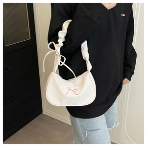 Close-up of white shoulder bag featuring pink bow embroidery and ruffled drawstring strap