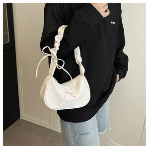 Close-up of white hobo bag featuring pink bow embroidery and ruffled shoulder strap detail