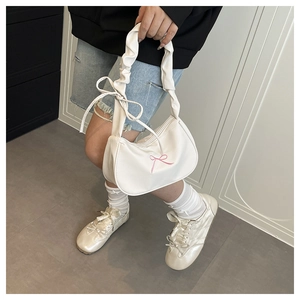 Close-up of white nylon shoulder bag with pink bow embroidery and pleated strap detail