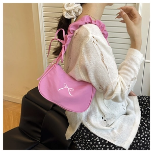 Pink nylon shoulder bag with ruffled strap and bow details in a lifestyle setting