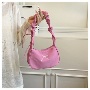 Pink underarm bag detail with ruffled handle and white embroidered bow on nylon fabric