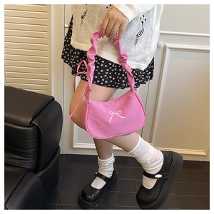 Detailed view of pink bow baguette bag with ruched handle in a cozy home setting