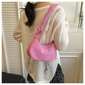 Close-up of pink fabric baguette bag with white bow print and knotted strap detail