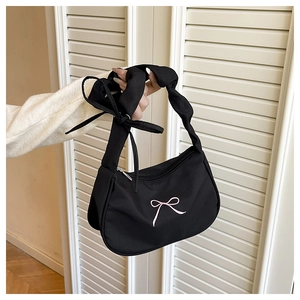 Detail of black fabric underarm bag featuring pink bow embroidery and ruffled strap design