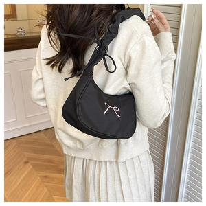 Detail of black crescent nylon shoulder bag with pink bow embroidery and pleated strap