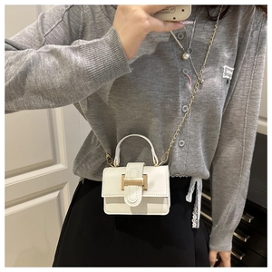 Close-up of the mini white leather crossbody bag with gold hardware and chain strap