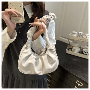 Detail of white pleated cloud bag featuring scrunchie handle and minimalist crescent design