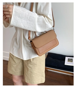 Detail of tan brown crossbody bag featuring woven texture flap and matte leather surface